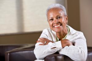 An older woman smiling with her arms crossed.