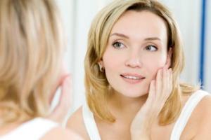 A woman looking at her reflection in the mirror.