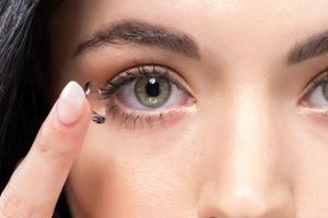 A woman holding a contact lens on her finger.