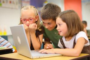 Elementary school students looking at a laptop.