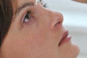 A woman applying eye drops.