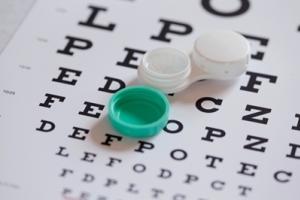 A contact lenses case on top of an eye chart.