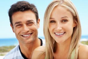 A man and woman smiling at the beach.