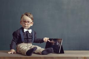 toddler sitting next to a tablet.