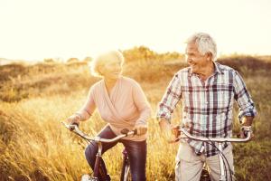 senior couple biking in field.