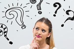 woman working on laptop with question marks around her.