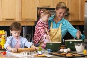 A mother smiling and baking with her kids.