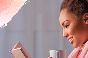 a woman reading and holding a mug.