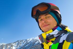 A man smiling with winter googles outdoors.