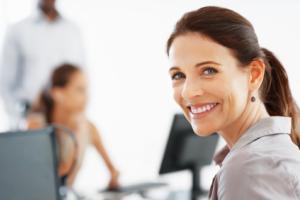 A woman smiling in front of a computer.