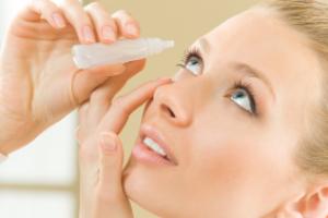 A woman applying eye drops.