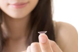 A woman holding a contact lens.