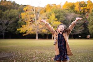 girl playing with fall leaves in the park