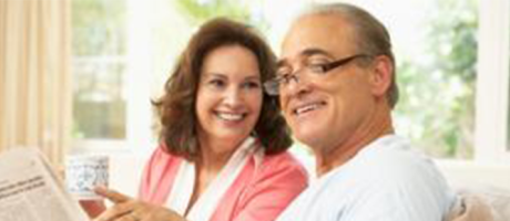 mature couple smiling and reading a newspaper