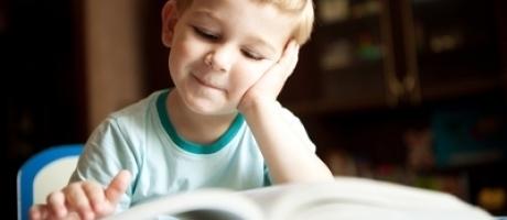 young boy smiling and reading