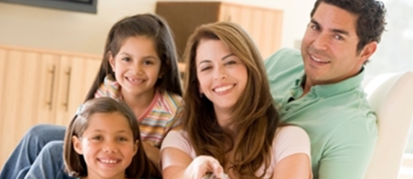 family smiling and watching television