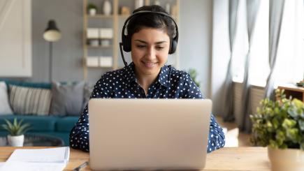 woman wearing a headset and working on her laptop. 