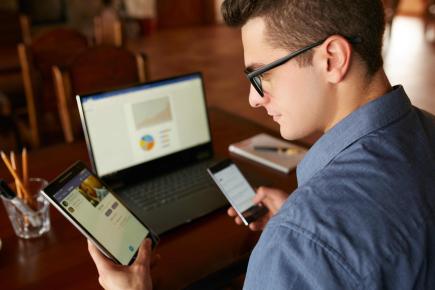 man working on laptop, tablet, and smartphone.